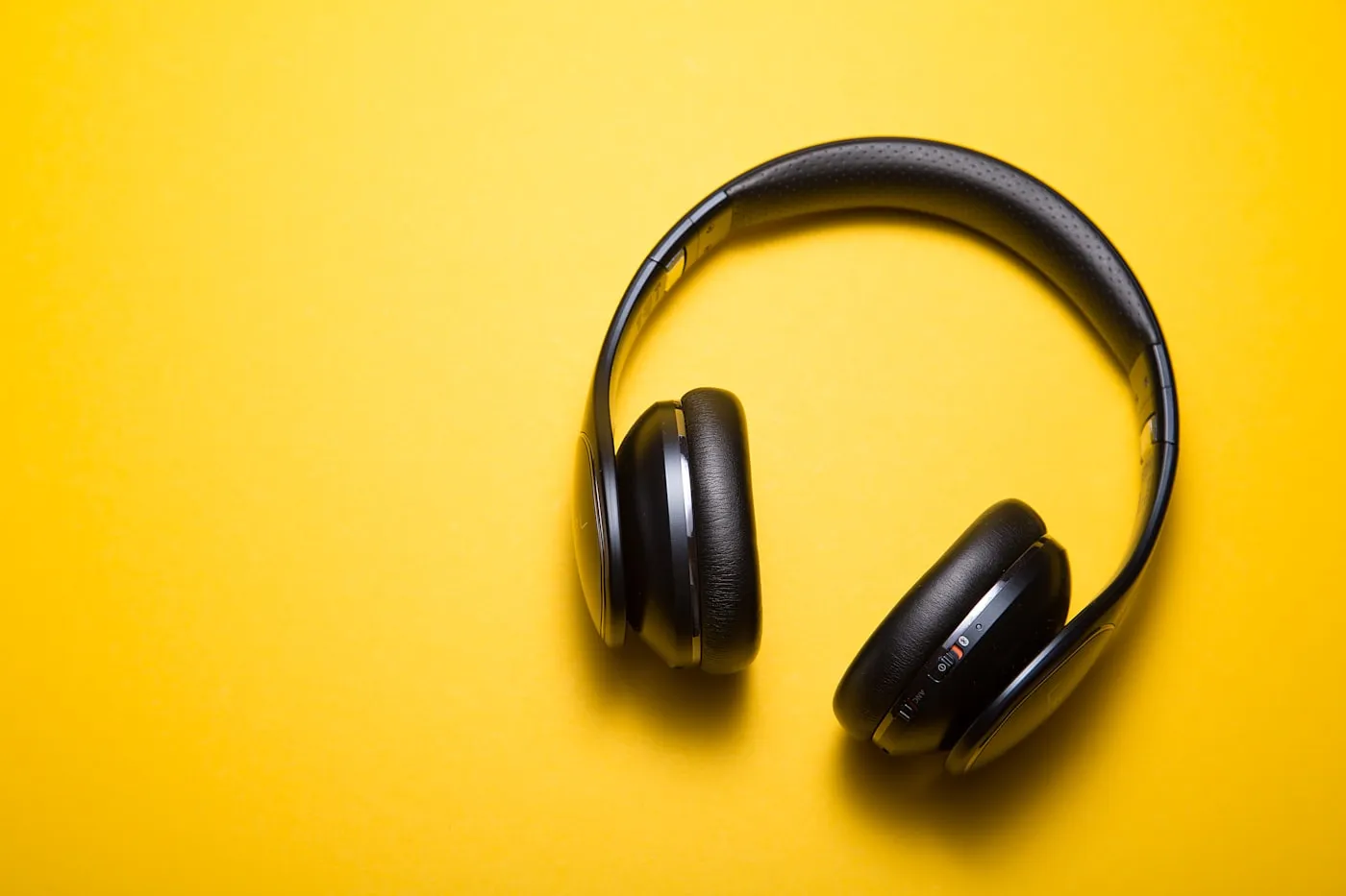 A pair of over-ear headphones on a yellow background