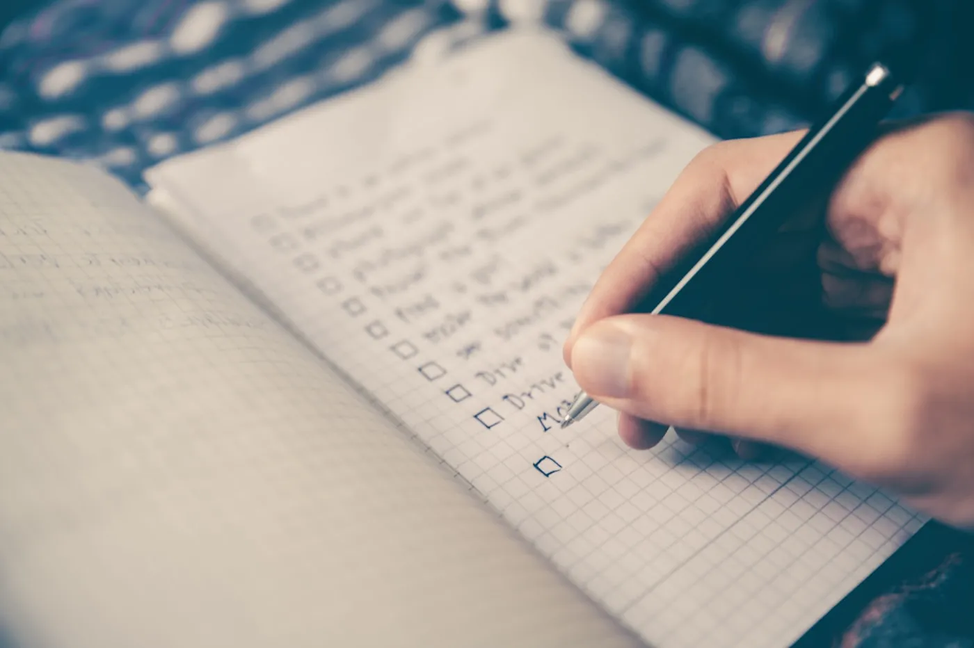 A hand ticking off items on a handwritten checklist